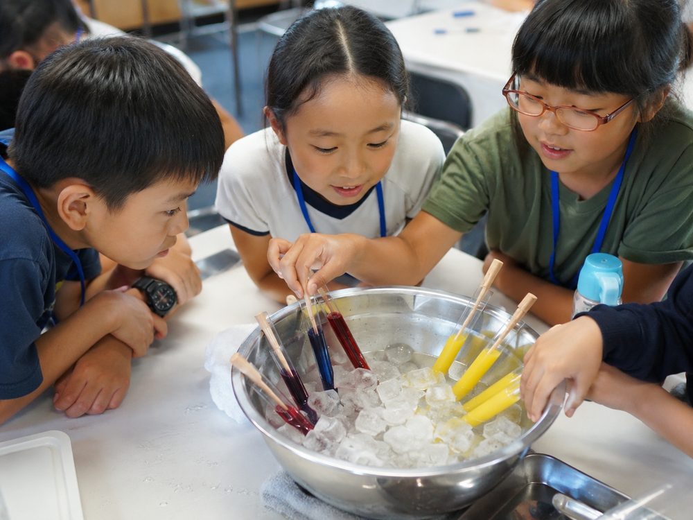 氷と塩でジュースを凍らせる子どもたち
