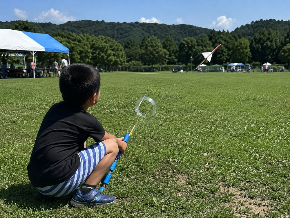 芝生広場でリングロケットを飛ばす男の子